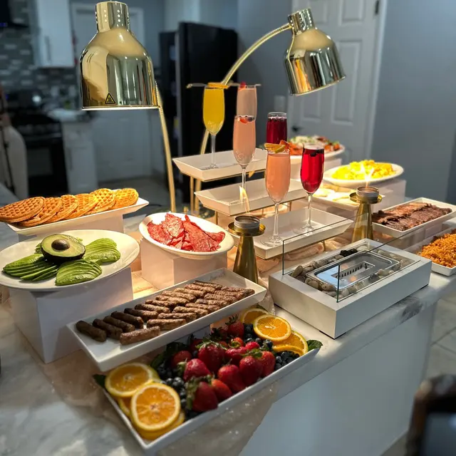 Brunch buffet under gold heat lamps — waffles, fresh fruit, and mimosas