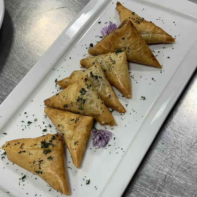 Crisp samosas, plated line with edible flowers